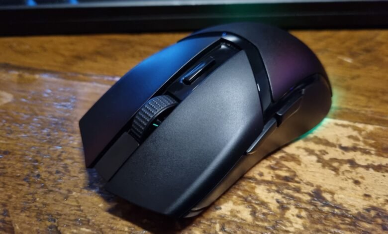 Close-up of a black wireless gaming mouse on a wood surface.