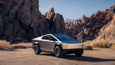 Tesla Cybertruck parked in a desert landscape with rock formations.