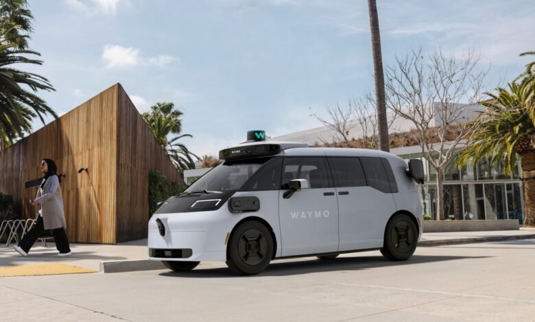 Waymo self-driving car parked near a woman walking on a sunny street.