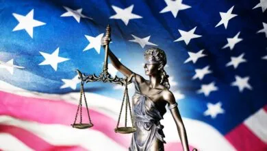 Statue of Lady Justice with scales against an American flag backdrop.