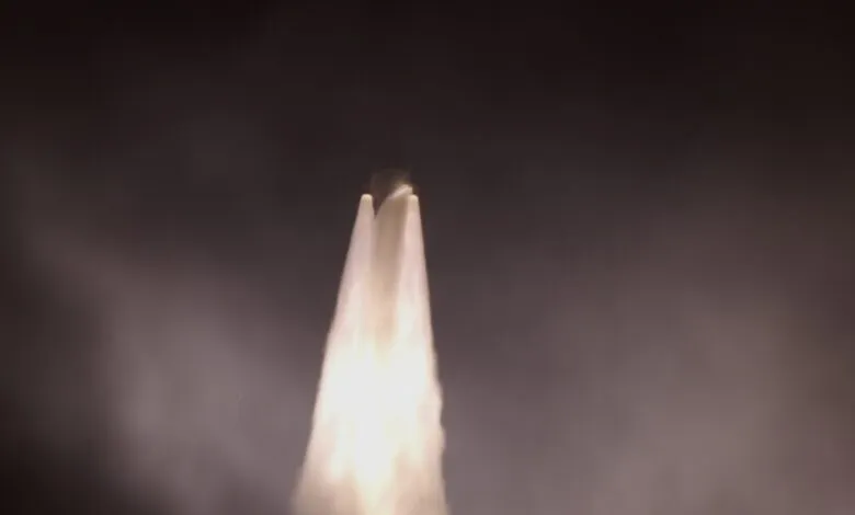 Rocket launch with bright plume against a dark sky.