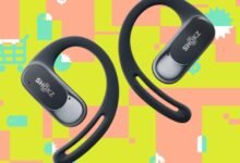 Two black Shokz OpenRun headphones against a colorful shopping-themed background.