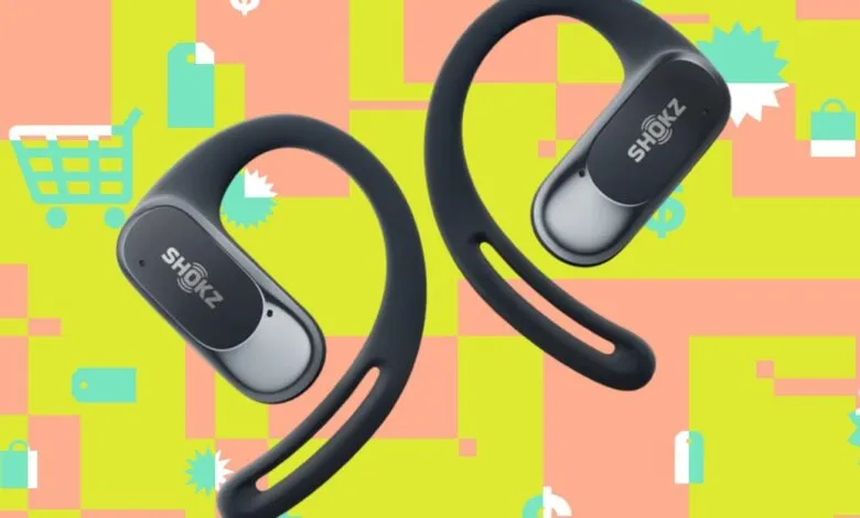 Two black Shokz OpenRun headphones against a colorful shopping-themed background.