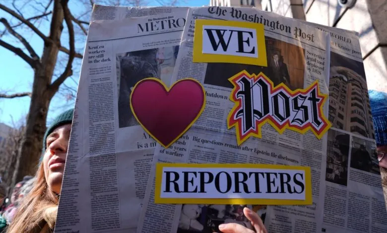 Person holding 'Washington Post' newspaper protest sign with 'WE <3 REPORTERS'.