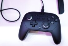 Black Nintendo Switch Pro Controller with cable on white surface.