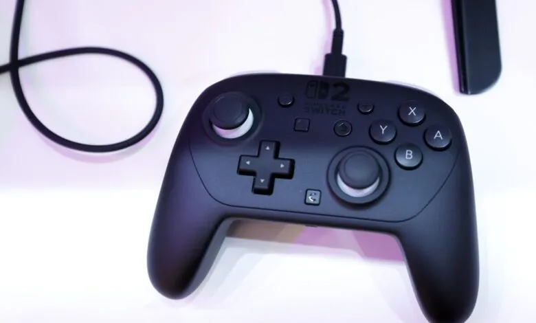 Black Nintendo Switch Pro Controller with cable on white surface.