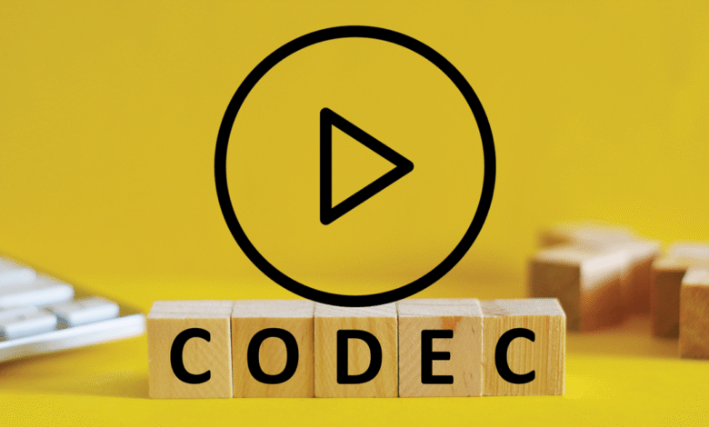 Wooden blocks spelling CODEC with play button on yellow background.