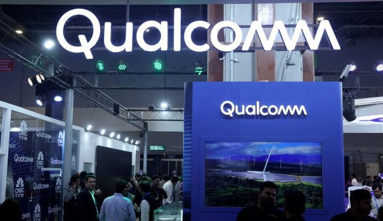 Qualcomm booth at a trade show, featuring bright signage and a display screen.