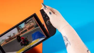 Nintendo Switch OLED being held, Mario Kart game displayed.