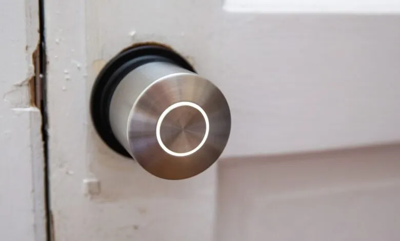 Smart lock installed on a white door with visible wear and tear.