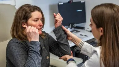 Doctor examines patient's arm in clinic setting.