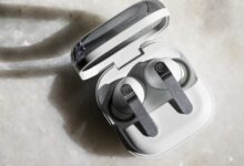 White wireless earbuds in open charging case on marble surface.