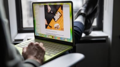 Person using a green MacBook with feet up on a windowsill.