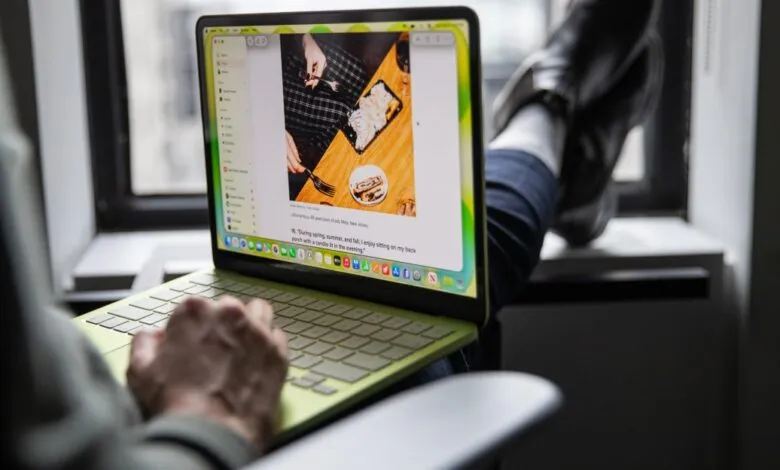 Person using a green MacBook with feet up on a windowsill.