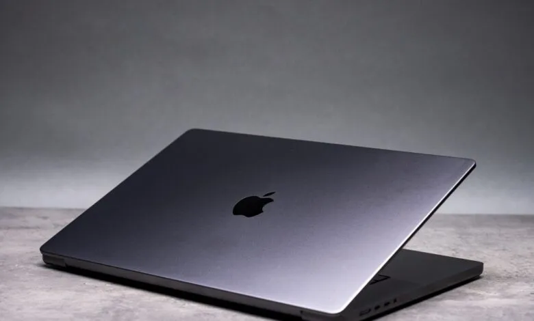 Space Gray Apple MacBook Pro with lid slightly open on gray surface.