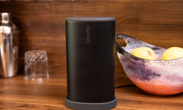Sonos Play speaker on a wooden surface with a bowl of fruit.