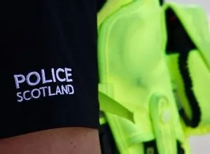 Close-up of a Police Scotland uniform with a bright yellow safety vest.