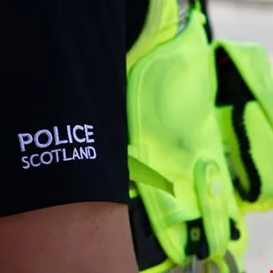 Close-up of a Police Scotland uniform with a bright yellow safety vest.