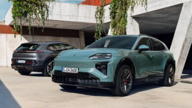 Two Porsche Macan EVs, one teal in front and one gray in back, parked outdoors.