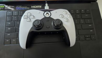 White and black Xbox controller rests on a black laptop keyboard.