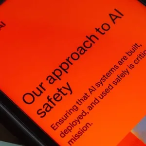 Close-up of a phone screen displaying text about AI safety on an orange background.