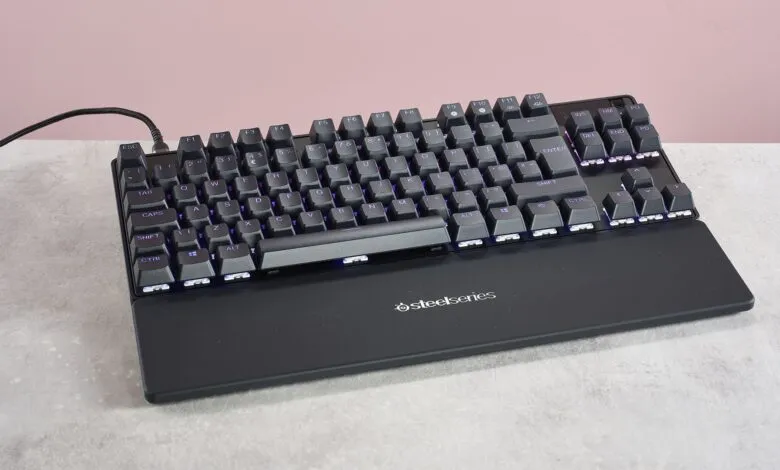 Black SteelSeries mechanical keyboard with purple backlighting.