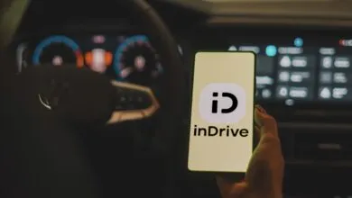 InDrive app displayed on phone inside a car.