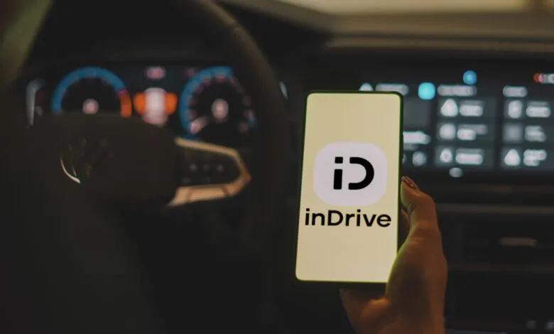 InDrive app displayed on phone inside a car.