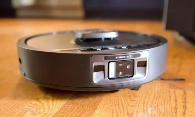 Robot vacuum cleaner on hardwood floor with stain detection feature.