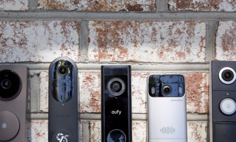 Five different smart video doorbells mounted on a brick wall.