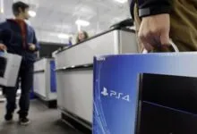 Shoppers purchase PS4 consoles at a retail store checkout.