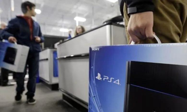 Shoppers purchase PS4 consoles at a retail store checkout.