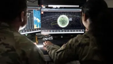 Two Space Force Guardians monitor satellite data on computer screens.