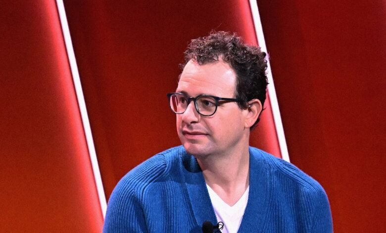 Dario Amodei, Anthropic CEO, wearing glasses and a blue sweater.