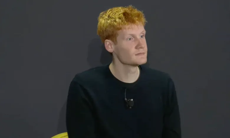Young man with red hair wearing a black shirt and lavalier microphone.