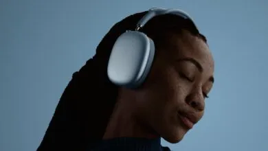 Woman with eyes closed wearing blue Apple AirPods Max headphones.