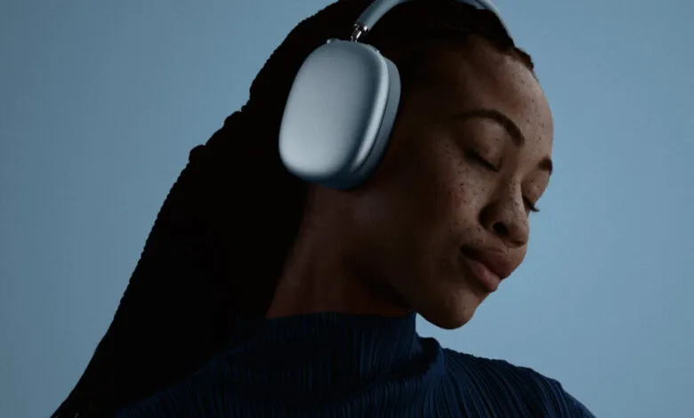 Woman with closed eyes wearing blue Apple AirPods Max headphones.