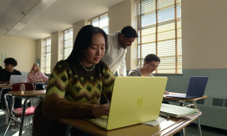 Students use colorful MacBooks in a sunlit classroom setting.