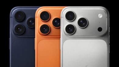Three iPhone models in navy, orange, and silver showing the camera array.
