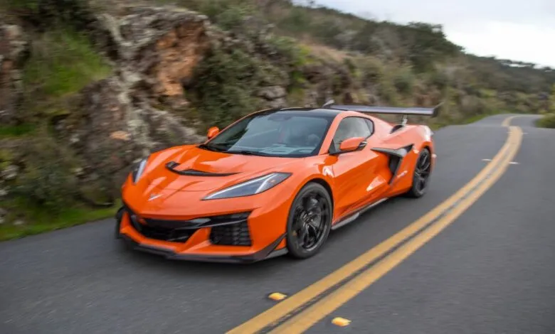 Orange Chevrolet Corvette Z06 driving on a winding road.