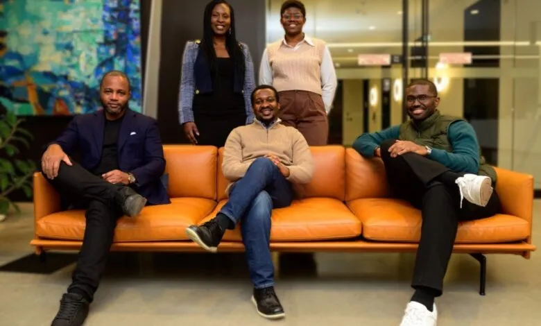 Group of five diverse professionals posing on and behind a modern orange couch.