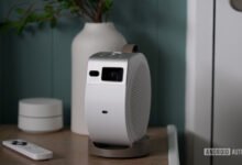 BenQ GV32 portable projector on a wooden surface with remote and decor.