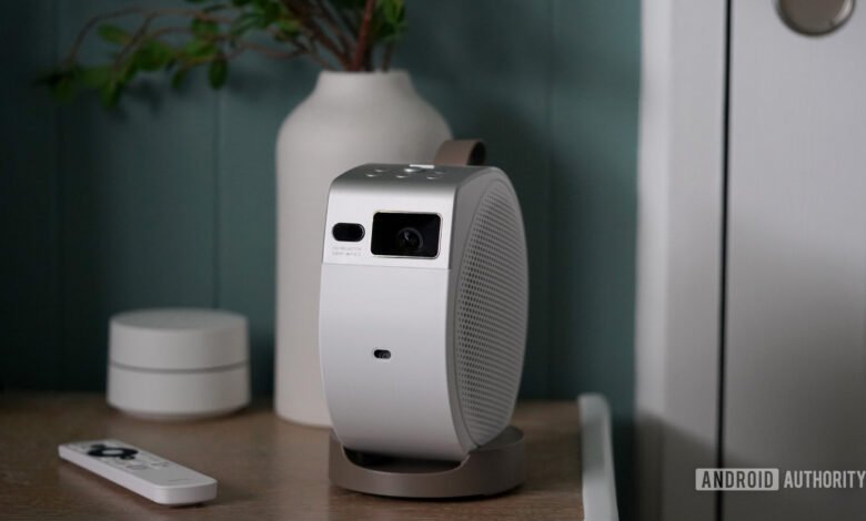 BenQ GV32 portable projector on a wooden surface with remote and decor.