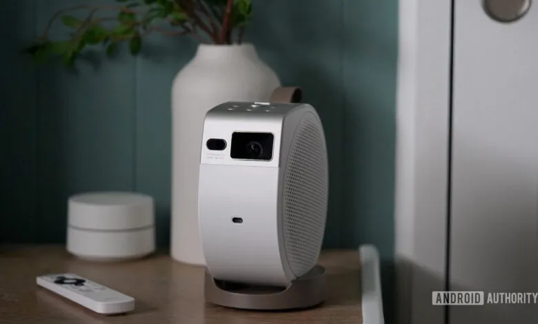 BenQ GV32 portable projector on a wooden surface with remote and decor.