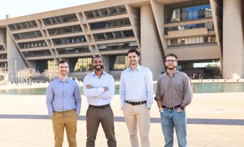 Four men stand in front of Dallas City Hall, smiling at the camera.