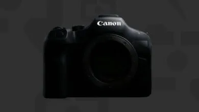 Close-up of a black Canon camera body against a dark gray patterned background.
