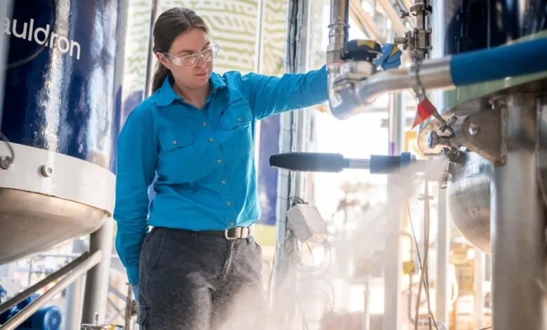 Woman in safety glasses working with industrial equipment and steam.