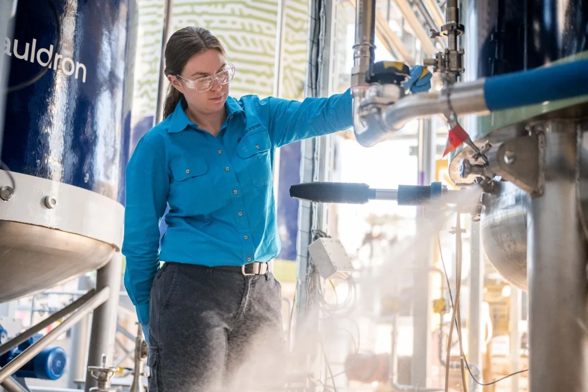 Woman in safety glasses working with industrial equipment and steam.