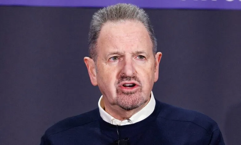 Man with gray hair and goatee speaking into a microphone.