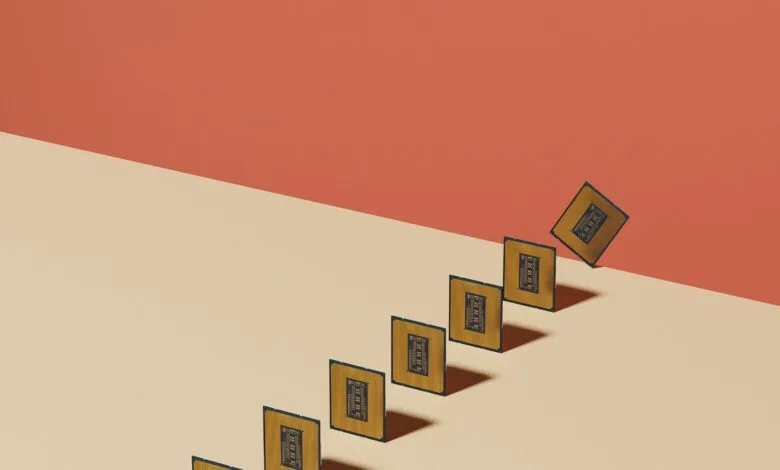 Several computer chips in a row, one falling off the edge, on a two-tone background.